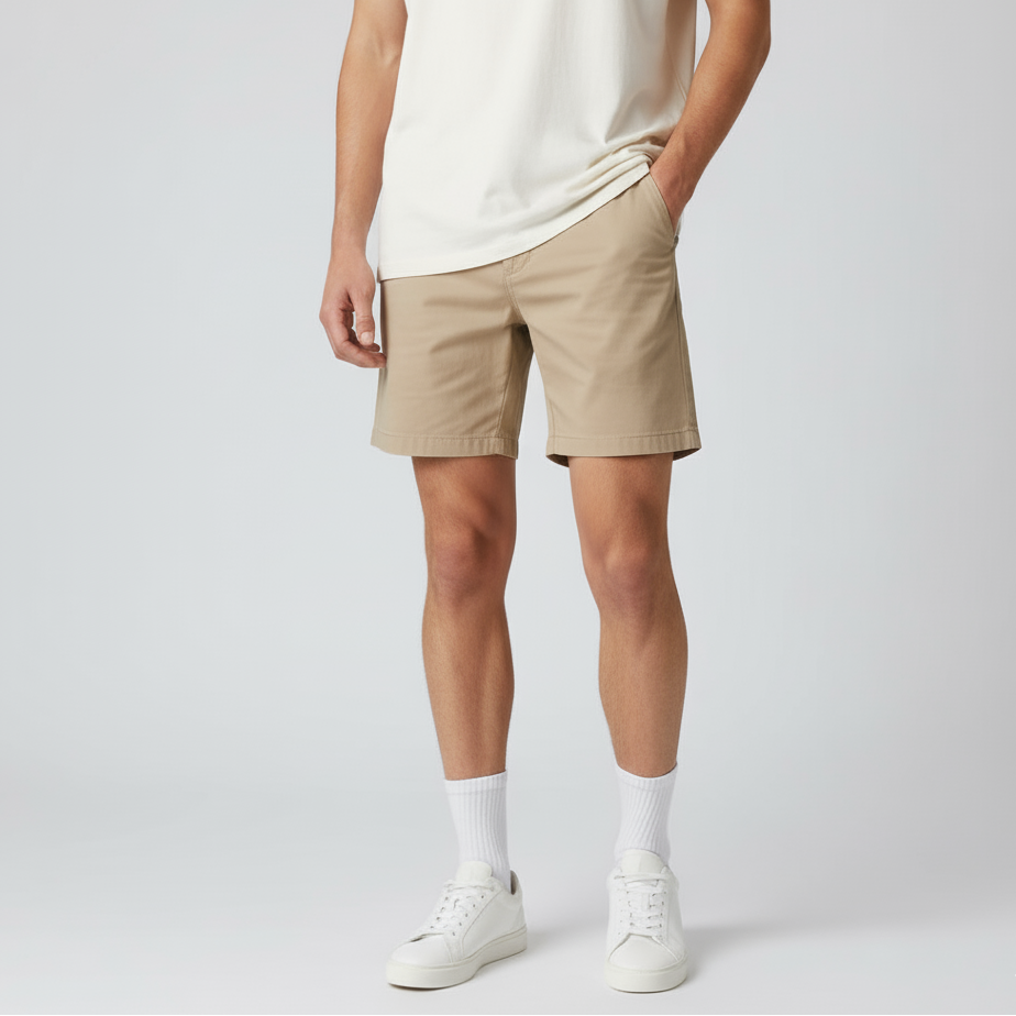 Person wearing beige shorts and white sneakers on a plain background