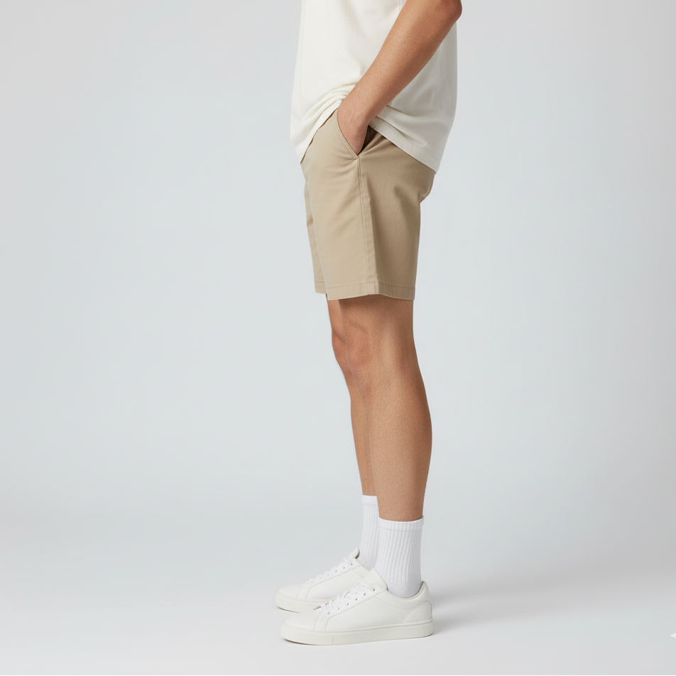 Person wearing beige shorts and white sneakers on a light gray background